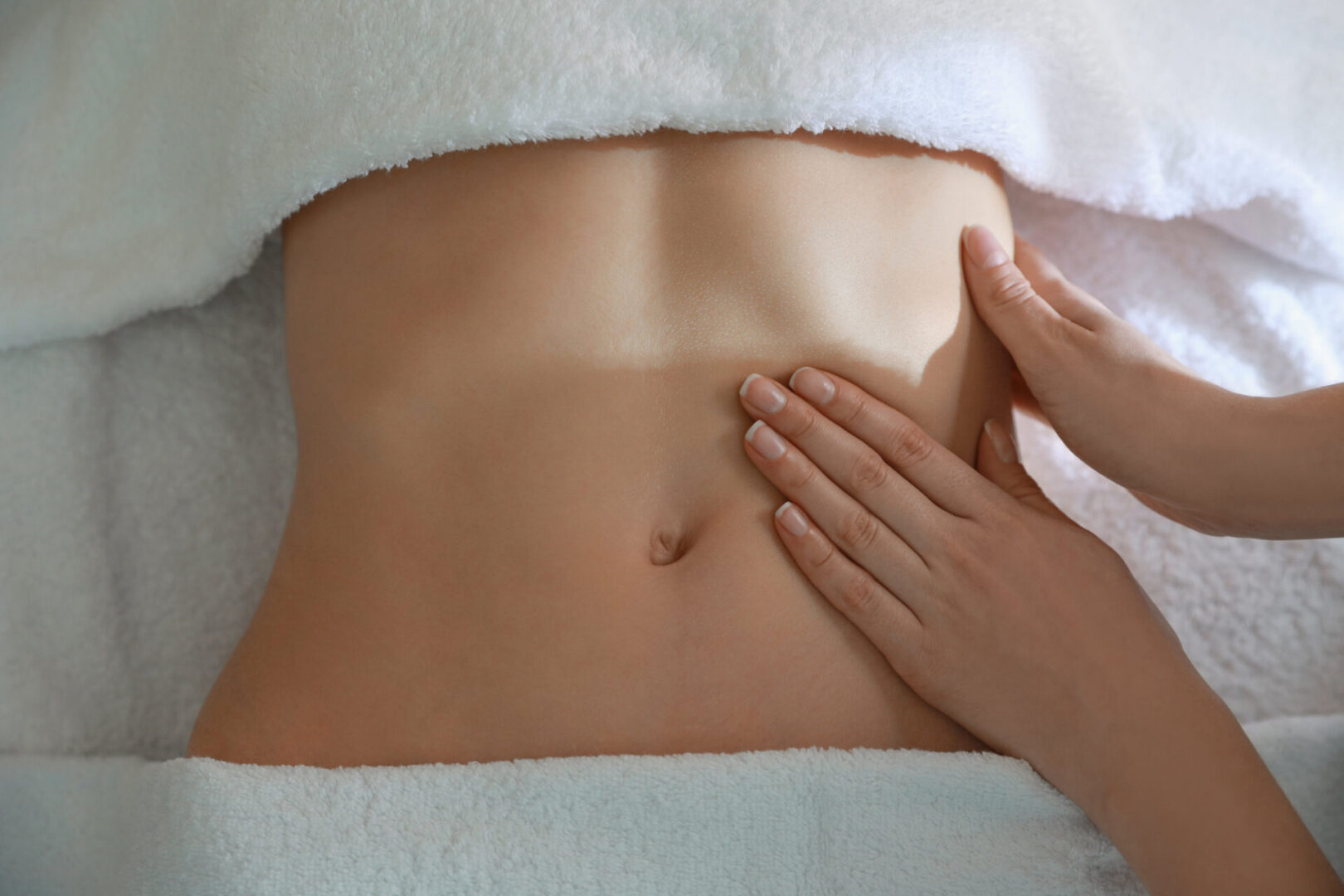 Woman receiving lymphatic drainage massage on her abdomen to help with her digestion, bloating, and detoxification