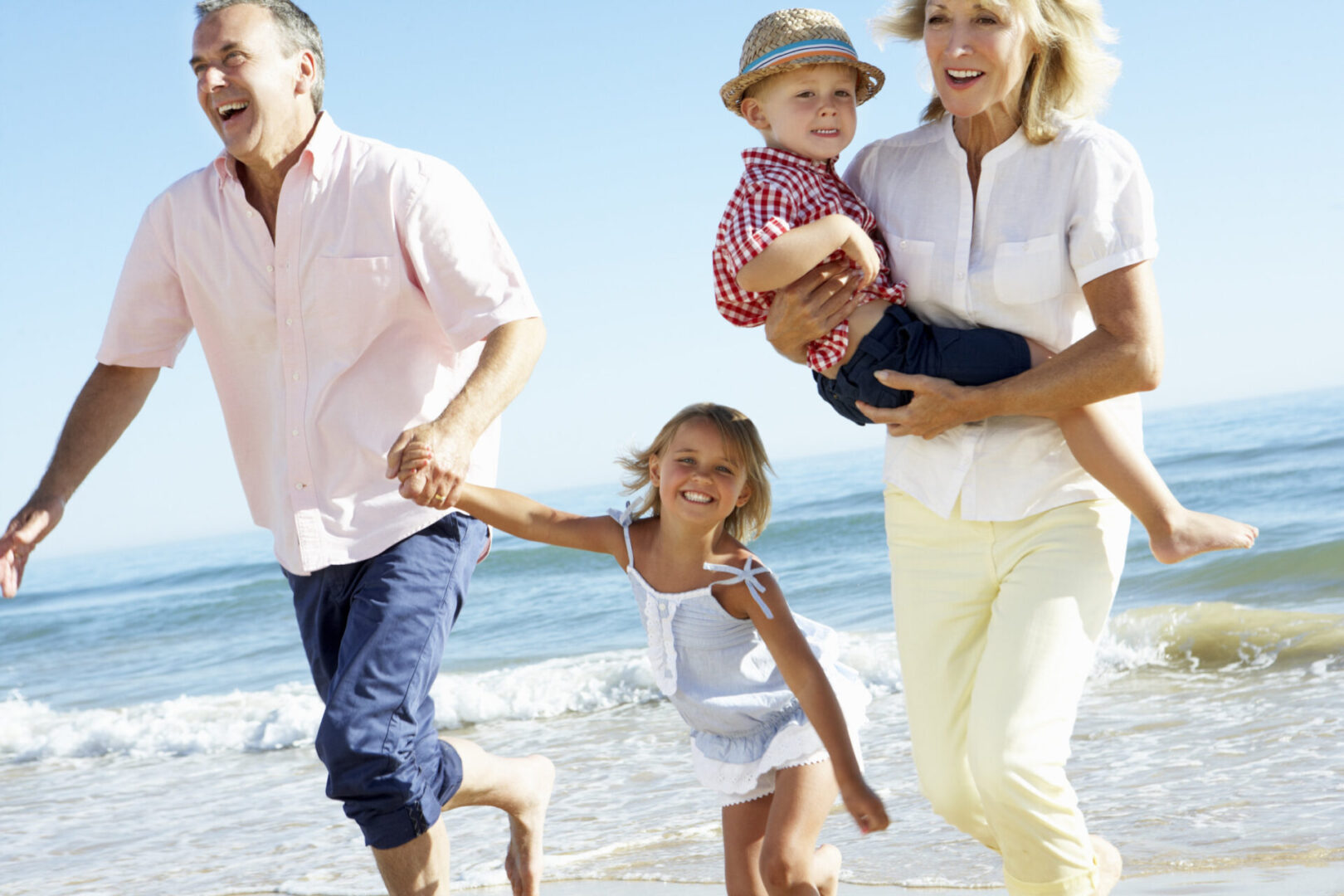 Grandparents running on the beach with their family being playful and energetic